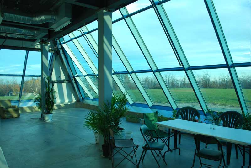 	A shot from within the first floor of our glass-fronted pyramid. Though there are only a few plants right now, our greenhouse space will soon be filled to the brim with a wide variety of plants and flowers.